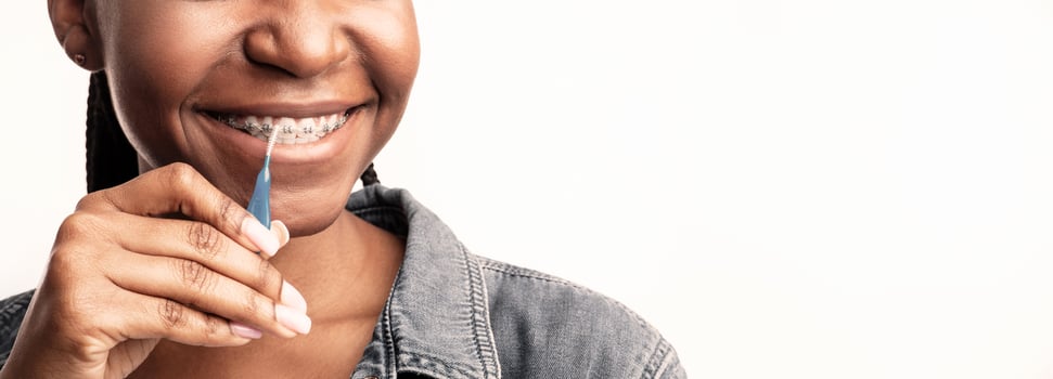 Orthodontics And Hygiene. Unrecognizable Black Lady Cleaning Teeth And Braces Posing On White Studio Background. Cropped, Panorama photo