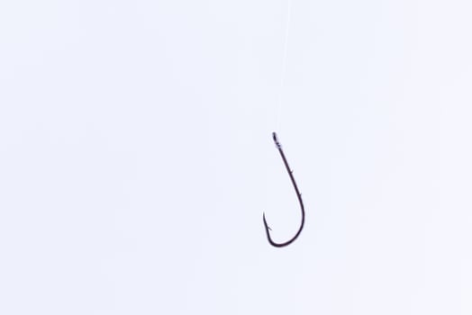 Black Fishing Hook Hanging on a Fishing Line Against a White Background photo