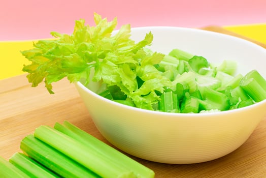 Fresh Chopped Celery Slices in White Bowl with Celery Sticks on Bamboo Cutting Board. Vegan and Vegetarian Culture. Raw Food. Healthy Diet with Negative Calorie Content photo