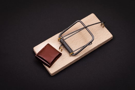 Temptation by Sweets or Chocolate Addiction - Sweet Wedge of Milk Chocolate in Wooden Mousetrap on Black Background photo