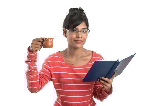 Beautiful young girl with book and cup of coffee posing on a white background. photo