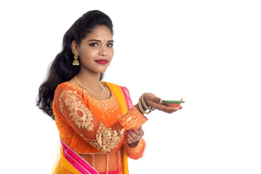 Portrait of a Indian Traditional Girl holding Diya, Girl Celebrating Diwali or Deepavali with holding oil lamp during festival of light on white background photo