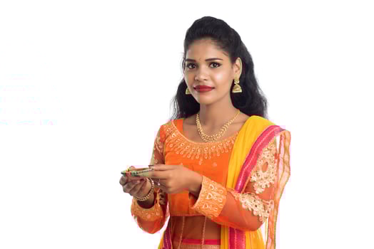 Portrait of a Indian Traditional Girl holding Diya, Girl Celebrating Diwali or Deepavali with holding oil lamp during festival of light on white background photo