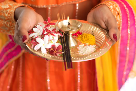 Beautiful Indian young girl holding pooja thali or performing worship on a white background photo