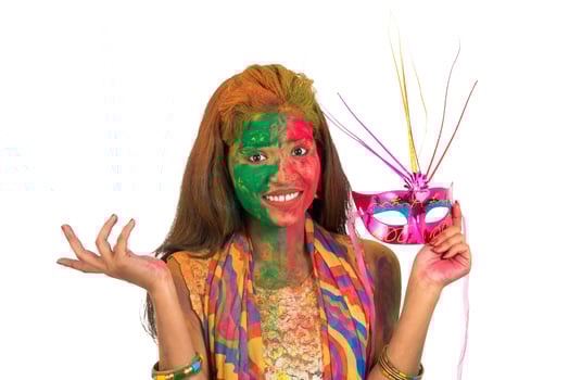 Girl with colorful face holding carnival mask and celebrating holi. photo