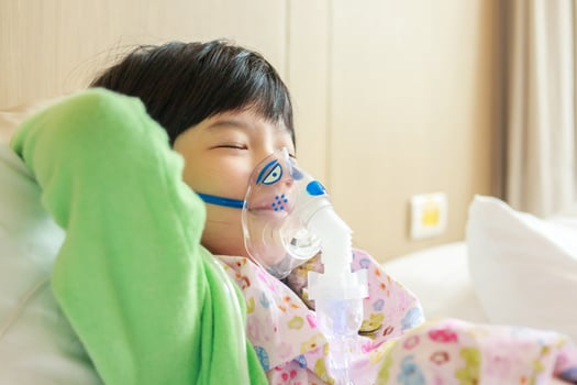 Sick little asian girl inhalation with nebulizer for respiratory treatment photo