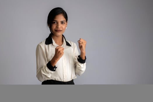Young smiling girl showing happiness of success on a grey background photo