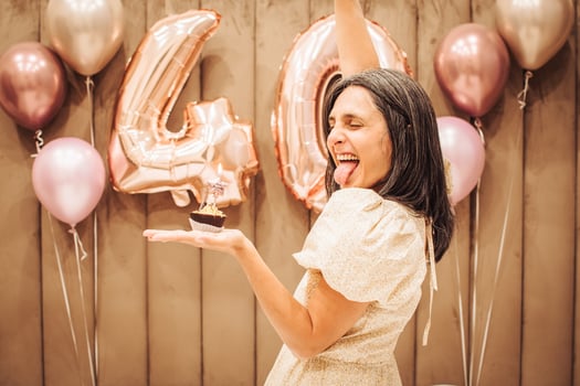 Adult happy beautiful woman forty years with festive cupcake with candle in hands, isolated on white, birthday girl. Natural proud young looking 40 years old woman celebrate maturity photo