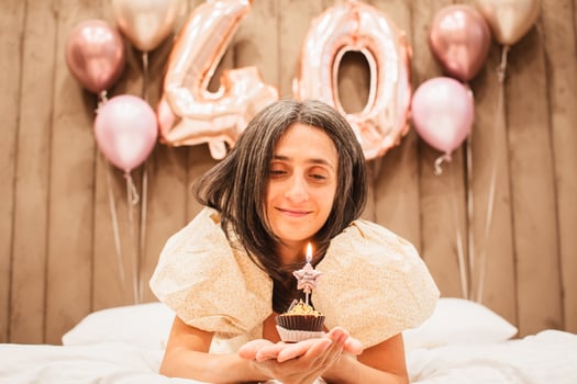 Brunette pretty beautiful caucasian woman in green festive dress blowing candle on a birthday party cupcake. Isolated white background photo