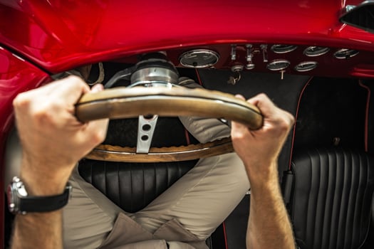 Driving a Classic Red Car With a Wooden Steering Wheel on an Open Road During Daylight photo