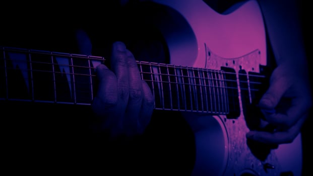 Guitarist Playing Guitar In Studio. Low key of man hand play white electric guitar for songs and cover music or skill practice. Close up of musician playing guitars instrument against black background photo