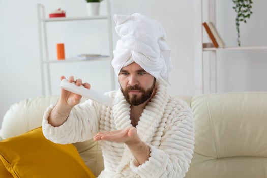 Bearded man holds white bottle cream or gel for skin care. Spa, body and skin care for man concept photo