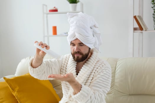 Bearded man holds white bottle cream or gel for skin care. Spa, body and skin care for man concept photo