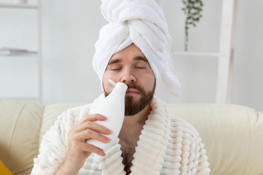 Bearded male with towel on his head applying body lotion cream. Guy smile when smell lotion cream on hand. Spa, body and skin care for man concept photo
