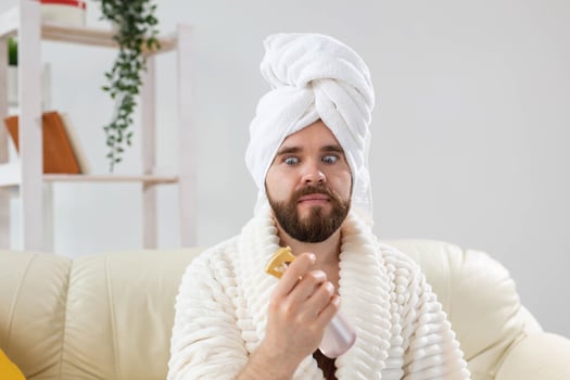 Bearded male with bath towel on his head applying spray water treatment on face. Spa, body and skin care for man concept. photo