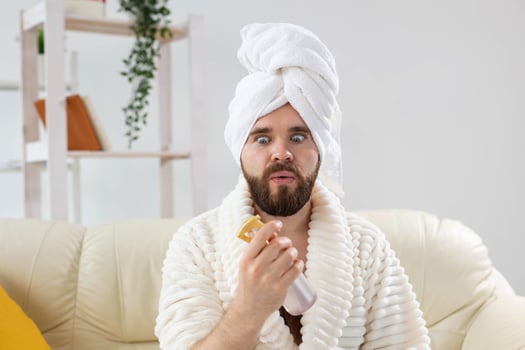 Bearded male with bath towel on his head applying spray water treatment on face. Spa, body and skin care for man concept. photo