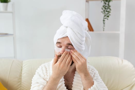 Bearded man applying eye patches on his face. Wrinkles and face home care for men. photo