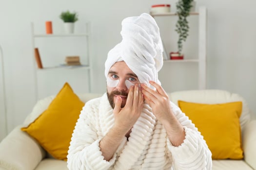 Bearded man sitting with eye patches on his face. Wrinkles and face home care for men. photo