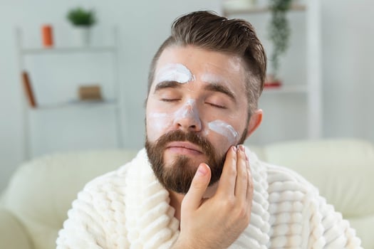 Bearded guy applying anti-wrinkle cream on his face. Skin care and spa for man concept. photo