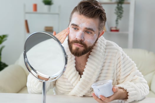 Bearded guy applying anti-wrinkle cream on his face. Skin care and spa for man concept. photo