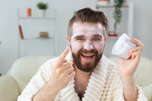 Bearded guy applying anti-wrinkle cream on his face. Skin care and spa for man concept. photo