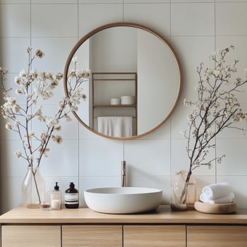 Elegant bathroom with round mirror and blooming branches in a serene setting photo