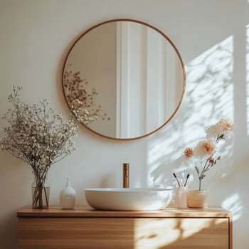 Elegant bathroom with round mirror and blooming branches in a serene setting photo