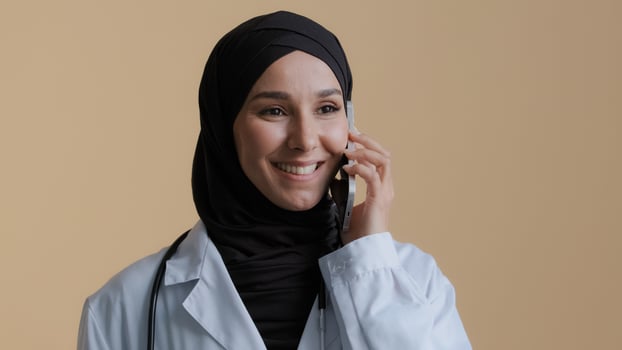 Arabian muslim young woman surgeon practitioner wear medical coat traditional hijab talk by cellphone consult patient remote female islamic therapist discuss treatment mobile conversation at clinic photo