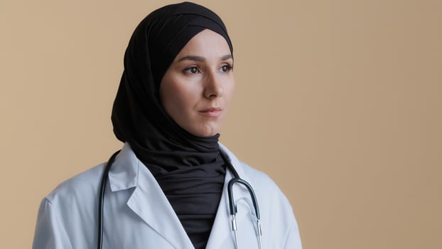 Portrait of pensive upset muslim arabian young woman doctor islamic gynecologist scientist physician in hijab headscarf thoughtful female medical pharmacist dreaming girl stand over beige background photo