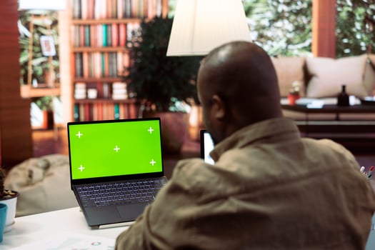 Businessman reviewing statistics reports next to an isolated mockup screen at home office, adviser calculating budget in order to expand the enterprise activity. Finance and economy. photo