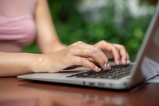 A close-up of a woman working on her laptop, typing on the laptop keyboard, working remotely. photo