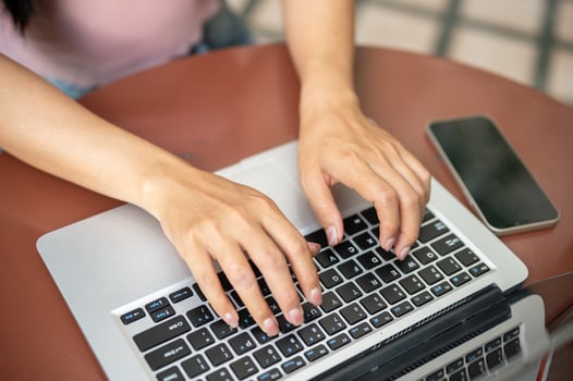 A close-up of a woman working on her laptop, typing on the laptop keyboard, working remotely. photo