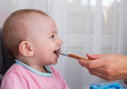 A mother's hand with a spoon and buckwheat porridge feeds a baby boy aged one year. Nutrition of children at an early age. Baby baby health food. Copy space for text, microelements photo