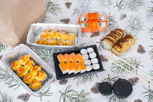 Delivery of sushi and rolls set top view on the table with a Christmas decor with a Christmas tree and a tablecloth with snowflakes, home cooking photo