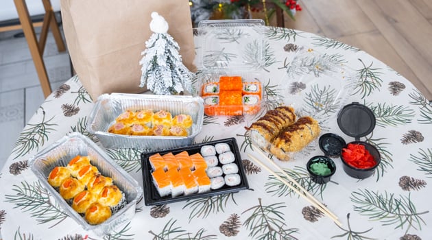 Delivery of sushi and rolls set top view on the table with a Christmas decor with a Christmas tree and a tablecloth with snowflakes, home cooking photo