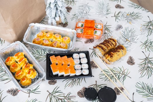 Delivery of sushi and rolls set top view on the table with a Christmas decor with a Christmas tree and a tablecloth with snowflakes, home cooking photo