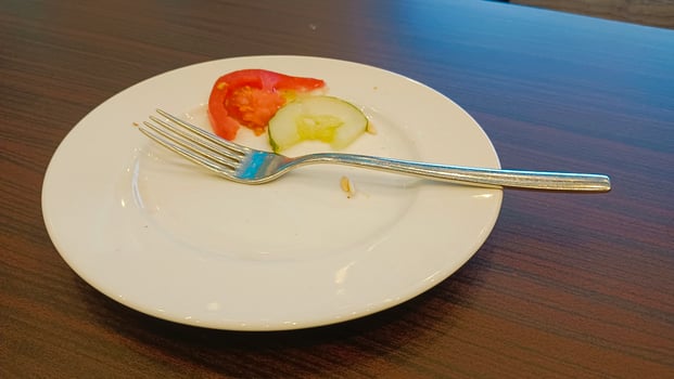 Empty plate with a fork, tomato and cucumber slices on a wooden table. photo