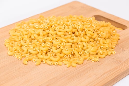 A Heap of Uncooked Chifferi Rigati Pasta on Wooden Kitchen Board. Fat and Unhealthy Food. Classic Dry Macaroni. Italian Culture and Cuisine. Raw Pasta photo