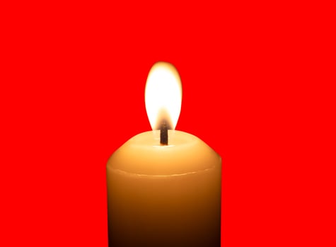 A single burning candle flame or light glowing on a big white candle isolated on red background with clipping path photo