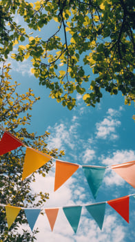 Colorful bunting flags hanging under lush green trees against a vibrant blue sky photo