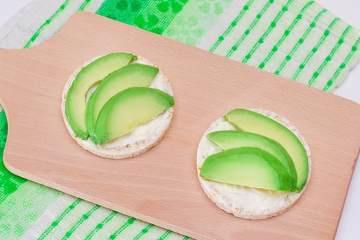 Rice Cake Sandwiches with Fresh Avocado and Cream Cheese on Wooden Cutting Board. Easy Breakfast. Diet Food. Quick and Healthy Sandwiches. Crispbread with Tasty Filling. Healthy Dietary Snack photo
