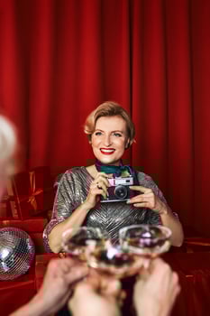 Cheerful beautiful photographer woman at the party celebration on red curtains background. Profession, party concept photo