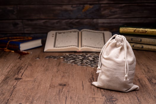 Hands holding a wooden bowl of rice grains and money bag for zakat, Islamic zakat concept. Muslims help the poor and needy. Conceptual shoot for property, income, and fitrah zakat. photo