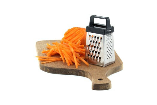 Grated carrots on a wooden cutting board with metal grater for healthy cooking and food preparation photo
