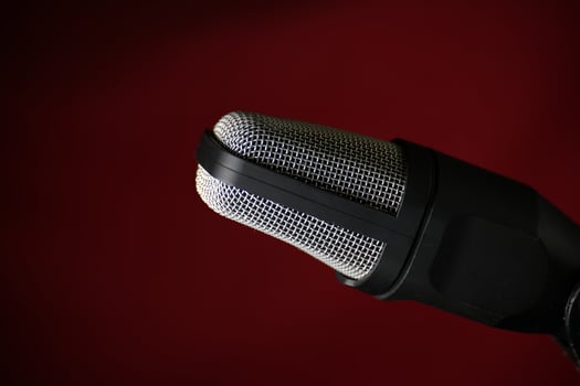 Professional studio microphone with metal mesh grille against dark red background photo
