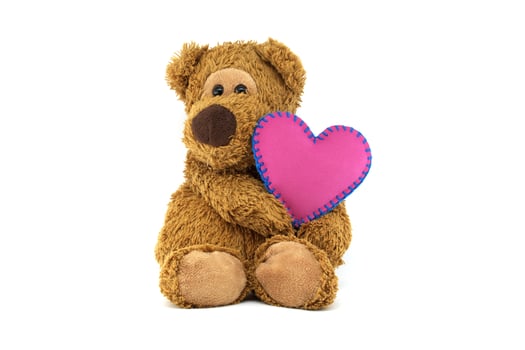 Teddy bear holding pink heart with blue stitching, expressing love and warmth on a white background photo