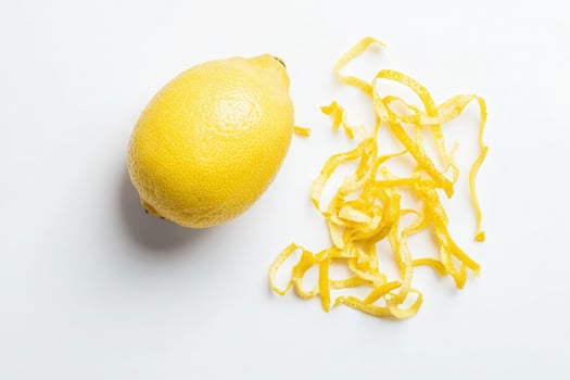 A vibrant whole lemon lies next to finely sliced lemon zest, showcasing the bright yellow color and fresh aroma. This arrangement highlights the fruits culinary potential and zests texture. photo