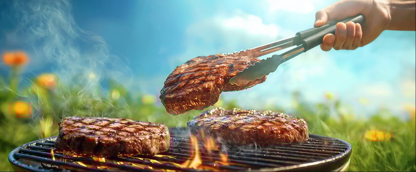 Chef holding steak with meat tongs over flaming grill, close-up, copy space photo