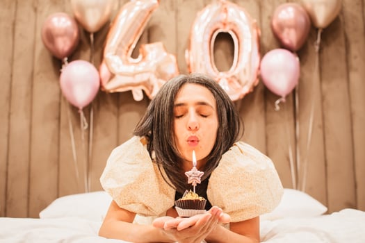 Adult happy beautiful woman forty years with festive cupcake with candle in hands, isolated on white, birthday girl. Natural looking mature woman celebrate happy birthday blow one cupcake candle photo