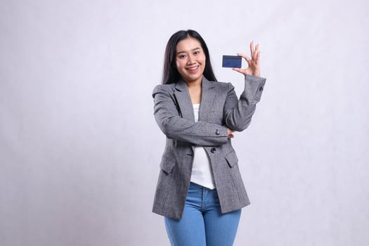 cheerful adult office woman beauty holding debit credit card wearing grey suit standing isolated on white background. for advertising content, lifestyle, finance, transaction photo